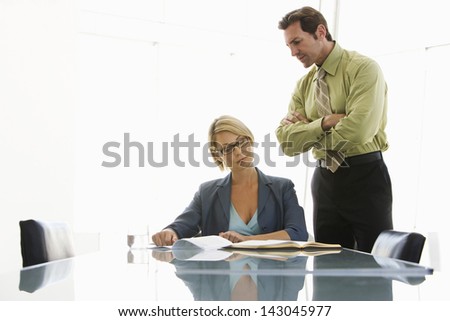 Young businesswoman with male executive reading document at conference table