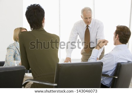 Mature businessman having discussion with team in conference room