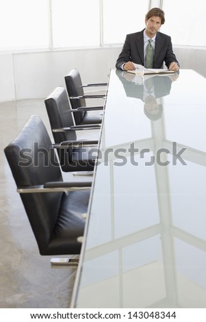 Portrait of young businessman with book at conference table