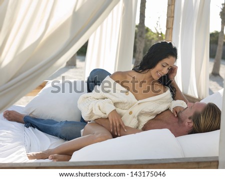 Romantic young couple in four-poster bed at beach