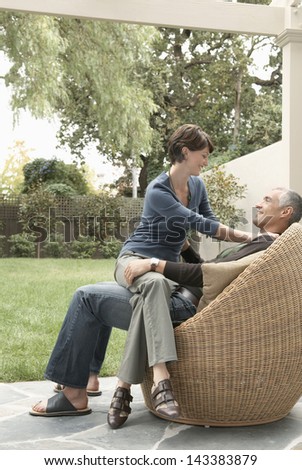 Full length of woman sitting on man\'s lap in lawn