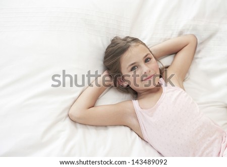 High Angle Portrait Of Cute Little Girl Lying In Bed With Hands Behind ...