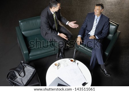 Full length of businessmen sitting on couches discussing at coffee table