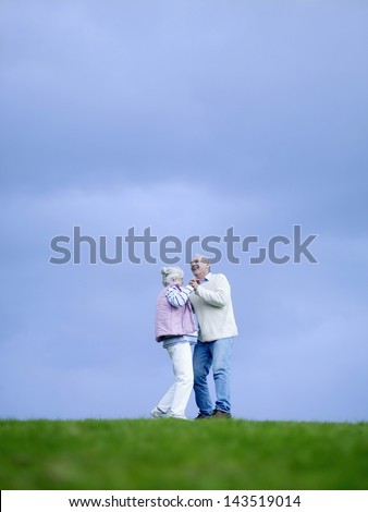 Full length of happy senior couple dancing on field