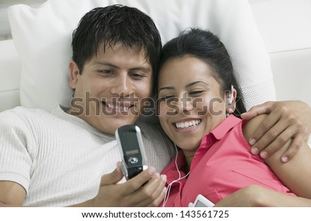 Closeup of a happy couple lying on couch and looking at picture on mobile phone