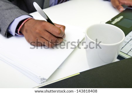 Close up of Indian mans hands writing on paper.