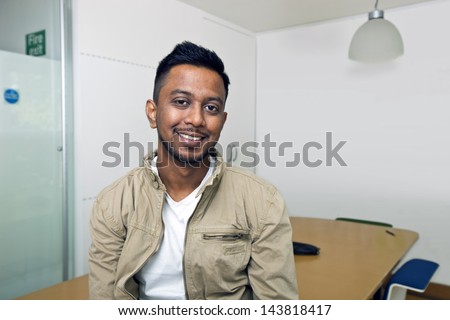 Young Indian man smiling at camera in his office