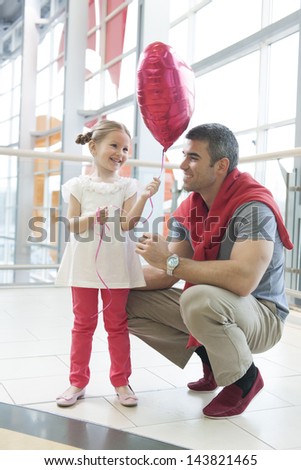 Father gives young daughter heart shaped balloon
