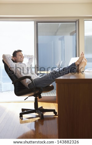 Happy businessman reclining with his feet up on desk