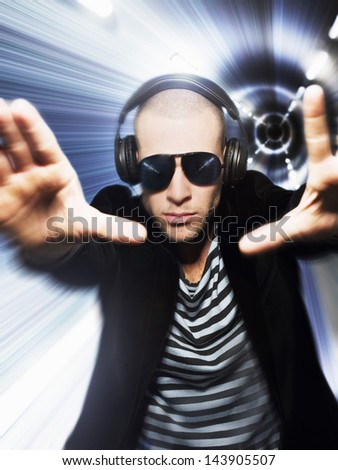 Man wearing headphones and sunglasses with hands out in front of tunnel effect