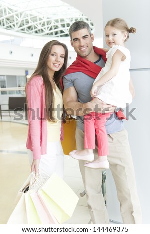 Father and mother pose with young daughter in shopping mall