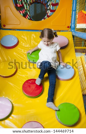 Young girl climbing down ramp in soft play center