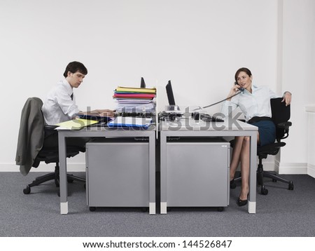 Side view of a hardworking man and relaxed woman in office
