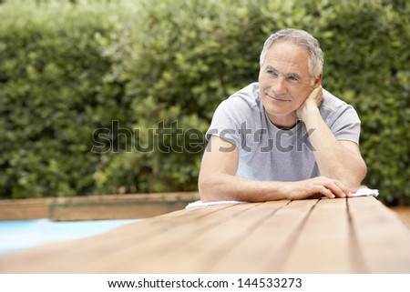 Happy middle aged man reclining by poolside