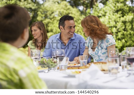 Happy parents looking at each other while having lunch with family in backyard