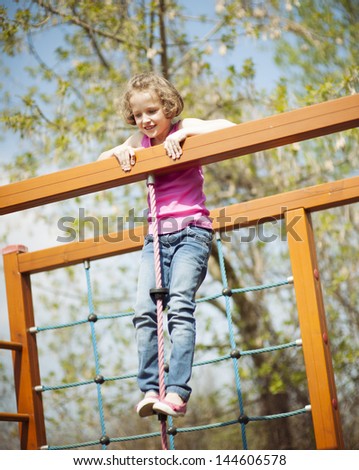 Young girl standing at top of rope and climbing frame