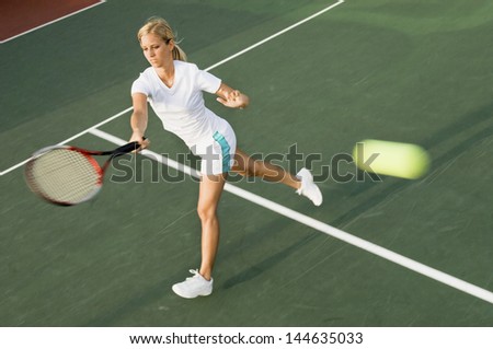 Female tennis player hitting tennis ball with forehand on court
