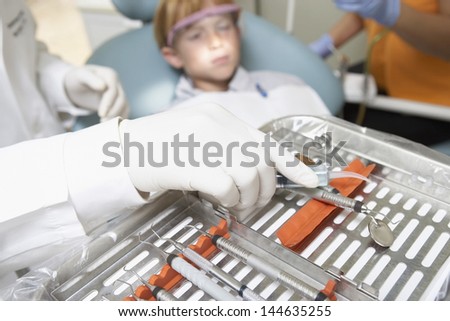 Blurred male patient with gloved hand and dental equipment in foreground
