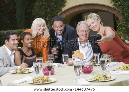 Group of multiethnic friends posing for photograph at the outdoor dining table