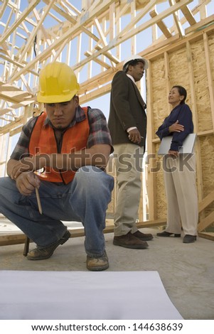 Two architects talking with construction worker looking at blueprints in foreground