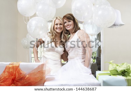 Portrait of a smiling bride and friend standing together by gift at bridal shower