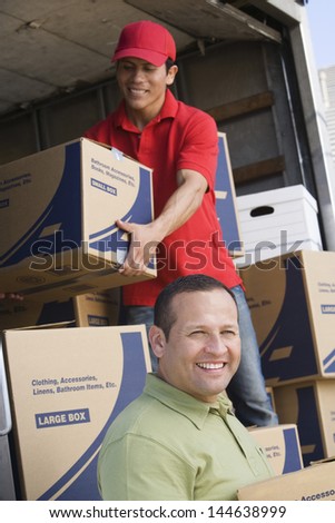 Portrait of a smiling man with worker unloading delivery van