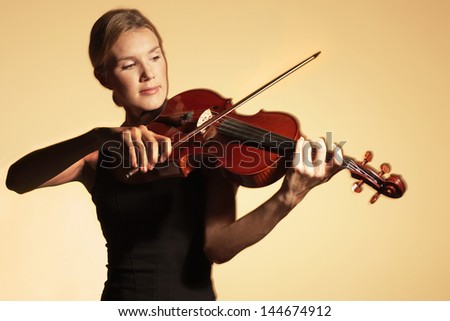Young woman playing the violin against colored background