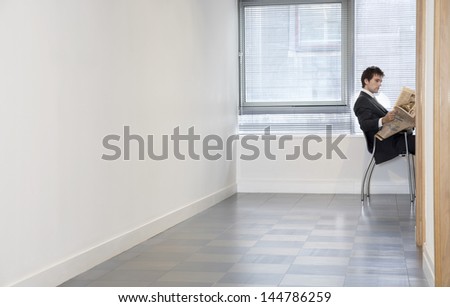Side view of a young businessman reading newspaper in an empty room