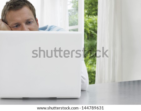 Man staring at laptop against window and garden