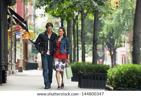 Full length of a smiling couple walking on sidewalk