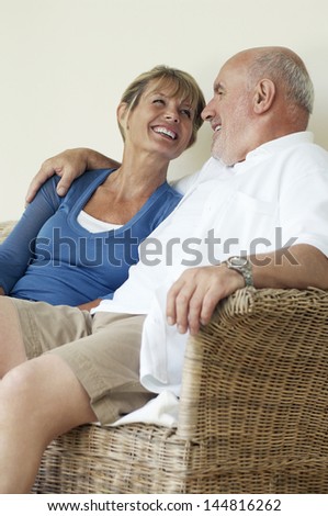 Relaxed and loving middle aged couple sitting on wicker couch