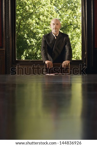 Portrait of confident middle aged businessman standing at conference table