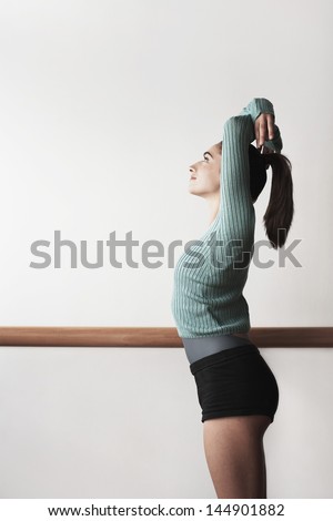 Side view of young female ballet dancer practicing at bar