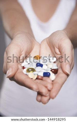 Closeup midsection of a woman holding colorful pills in hands
