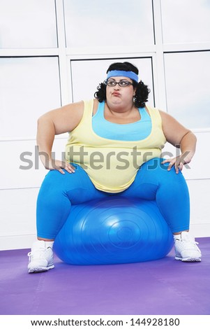 Full length of an overweight woman sitting on exercise ball