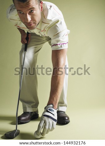 Golfer with golf club and ball against colored background