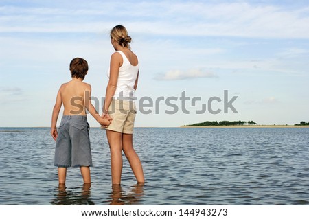 Rear view of mother and son holding hands while enjoying the sea view