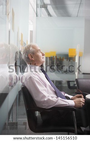 Side view of thoughtful middle aged businessman sitting on office chair