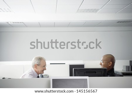 Multiethnic business people having casual meeting in office cubicle