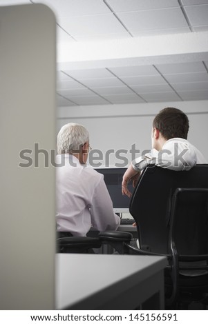 Rear view of business people using computer in office cubicle