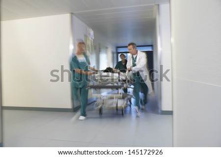 Medical workers moving patient on gurney through hospital corridor