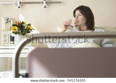 Female patient drinking water in the hospital bed