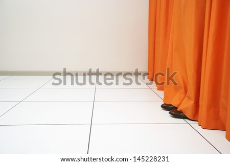 Person hiding behind orange curtain