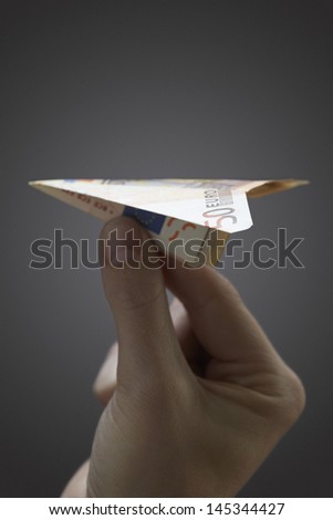 Person holding paper airplane made of 50 euro note close-up of hand