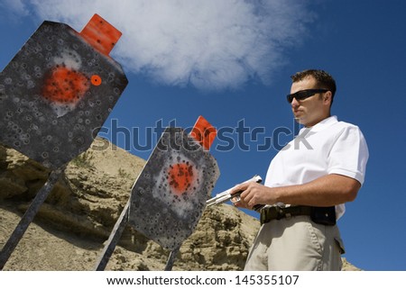 Man holding hand gun near targets at firing range