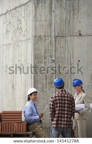 Construction team with blueprint communicating at site