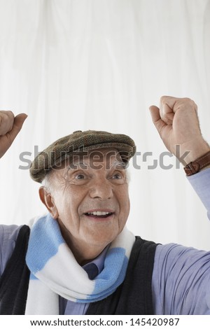 Closeup of a cheerful senior man in football scarf celebrating against white background