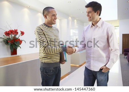 Casually dressed happy multiethnic businessmen shaking hands in office