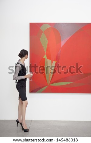 Full length of a woman looking at painting in art gallery