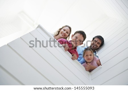 Low angle view of happy parents with children looking over white wall